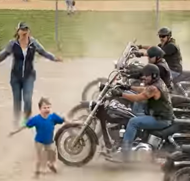 Un ragazzino corse sul campo e tese le braccia per fermare un convoglio di motociclisti in rapida avvicinazione, urlando: “Non avvicinatevi!” —ma cosa aveva visto che nessun altro aveva notato?